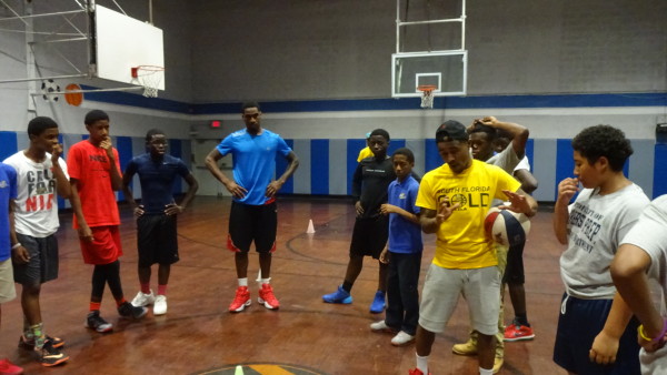 A group of young men standing around in a gym.