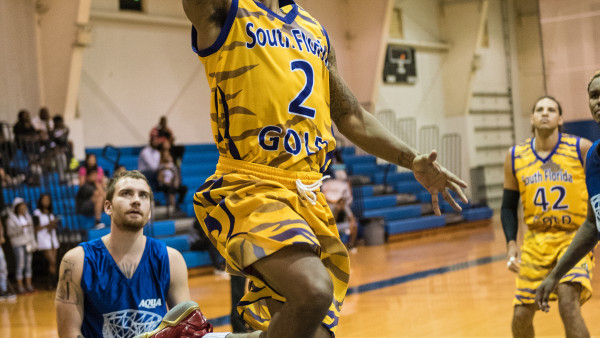 A basketball player is jumping in the air to dunk.