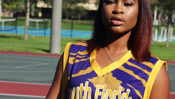 A woman in a basketball uniform standing on the court.