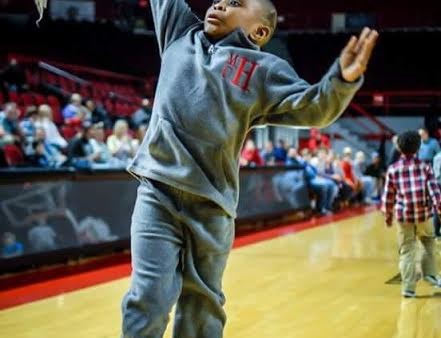 A young boy is playing basketball on the court.