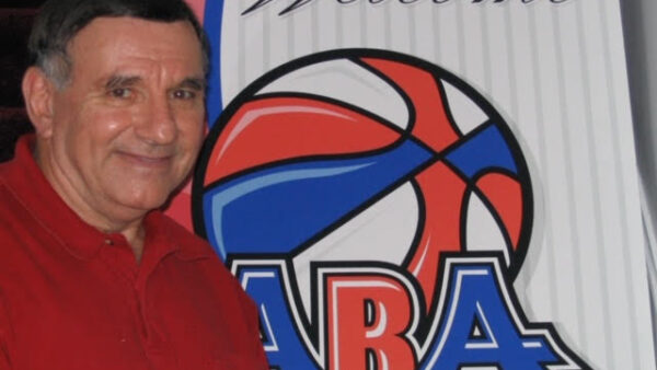 Man in red shirt standing near ABA logo.