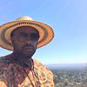 A man in a straw hat standing on top of a hill.