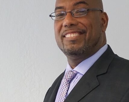 A black man in a suit and tie smiling.