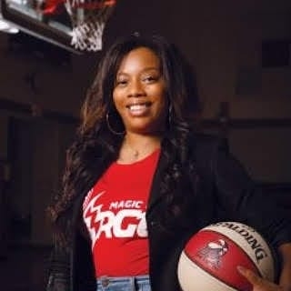 A woman holding a basketball in front of a basket ball hoop.